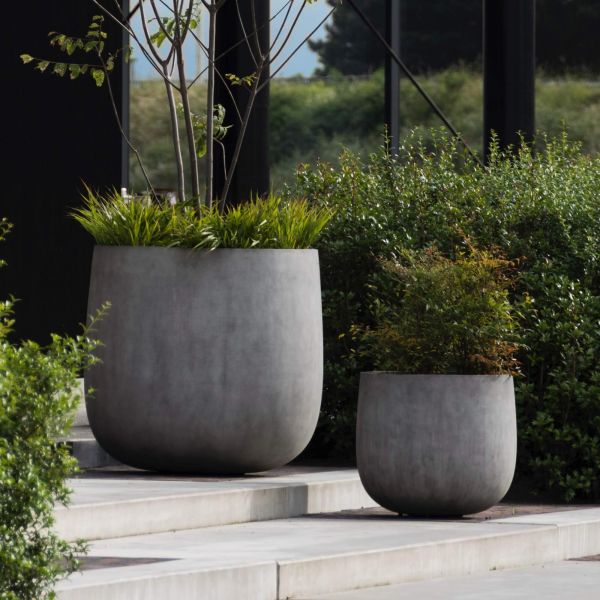 Two round planters with a smooth, concrete-like finish decorate outdoor steps
