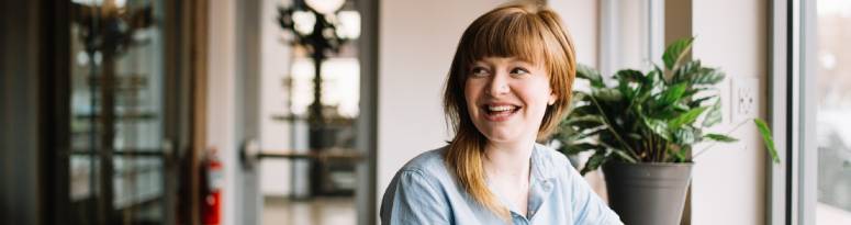 happy woman sitting at desk with plant in background
