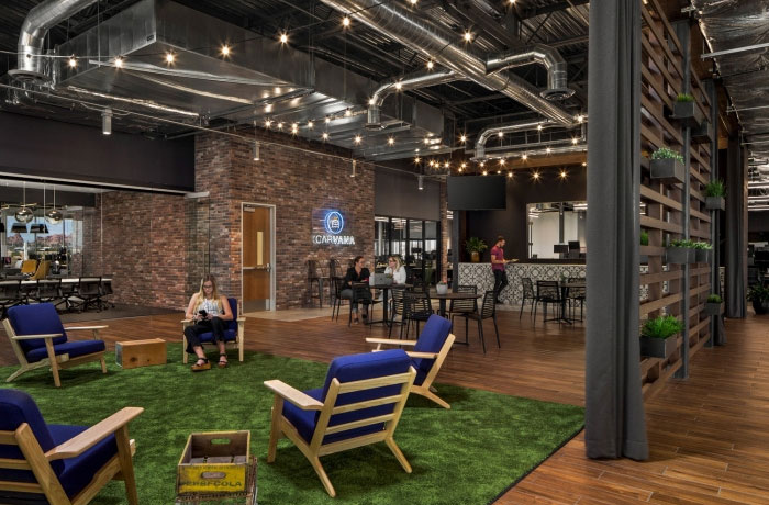carvana office with exposed industrial ceiling, exposed brick, a green carpet to imitate grass, and hanging wall plants