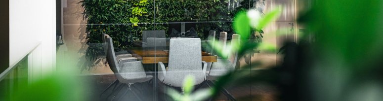 A modern office conference room with a lush green vertical garden visible through glass walls