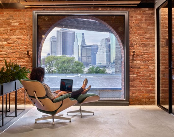 image of part of the united technologies digital office with exposed brick wall and a rounded window looking out into a city