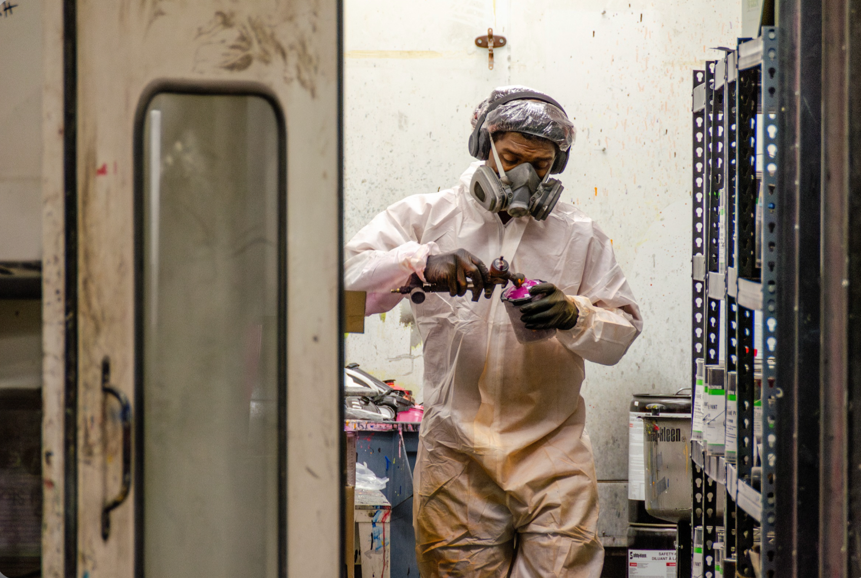 Person in protective suit and mask spray painting planter